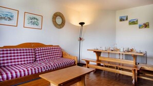 A room with a checkered sofa, a wooden table with benches, and framed pictures on the walls. - 150m from ski slopes, 5th floor, view mountain, balcony, parking, ski locker, 36m², Valfréjus (Valfréjus)