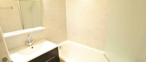 A bathroom with a white sink, a mirror, a black vanity, and a bathtub.