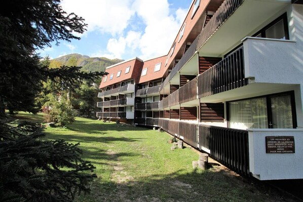 Un edificio de varios pisos con balcones, un área verde al frente y un letrero en francés.