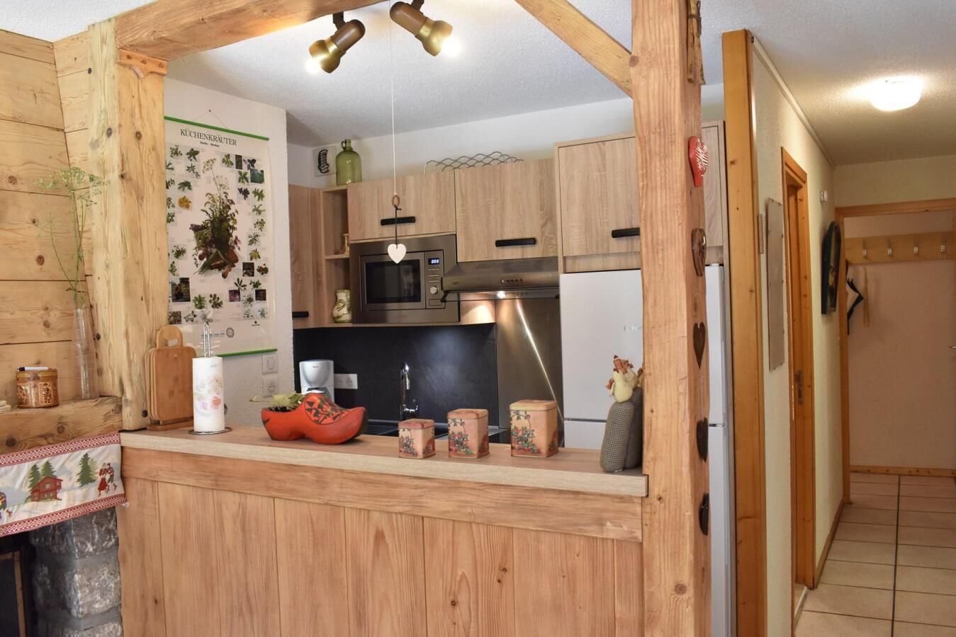 A kitchen with wooden cabinets, a microwave, a refrigerator, and a wooden counter with various items.