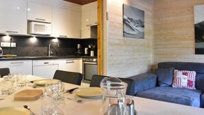 A modern kitchen with white cabinets, a microwave, and a dining area with a table set for four.