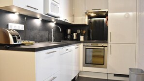 A modern kitchen with white cabinetry, a built-in oven, a microwave, and a toaster.