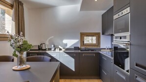 A modern kitchen with a central island, built-in appliances, and a window providing natural light.