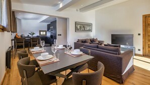 A modern living room with a dining area, a sofa set, and a flat-screen TV.