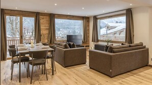 Una sala de estar moderna con una mesa de comedor, sofás y grandes ventanales que ofrecen vistas a un paisaje nevado.