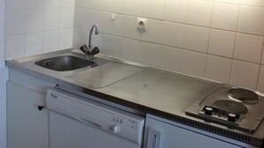 Een kleine keuken met een inbouwvaatwasser, een magnetron en een spoelbak.