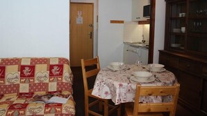 Een gezellige woonkamer met een bank en een eettafel voor vier personen.