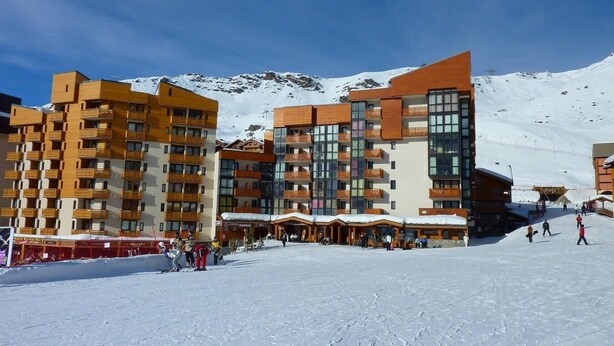 Een modern skigebied met meerlaags gebouwen, skiliften en een besneeuwd landschap.