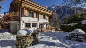 Eine zweistöckige Holzhütte mit Balkon, umgeben von Schnee und Bergen.