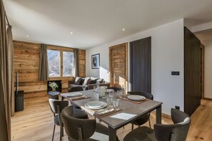 Enjoy meals in this stylish dining area with a long table for four, comfortable sofa, and modern chairs.