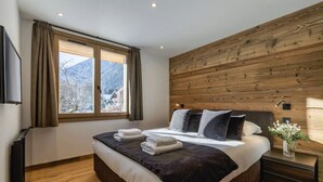Un dormitorio con una cama grande, pared de paneles de madera y una ventana con cortinas.