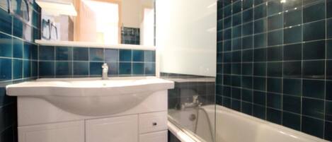 Un baño con un lavamanos blanco, un espejo y una bañera.