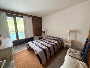 A bedroom with a bed, a desk, a chair, a lamp, and a view of the outdoors. - Ski-in/ski-out & foot of the slopes, 2nd floor, view ski slopes, balcony, tv, 48m², Montgenèvre (Montgenèvre)