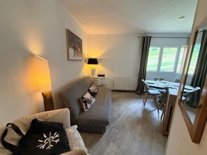 A living room with a sofa, a table, and a chair. There is a window with curtains, a lamp, and a picture on the wall. - Ski-in/ski-out & foot of the slopes, 2nd floor, view ski slopes, balcony, tv, 48m², Montgenèvre (Montgenèvre)
