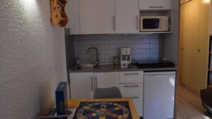 A compact kitchen with white cabinets, a microwave, a small sink, and a refrigerator. - 100m from shops, 2nd floor, view mountain, balcony, parking, tv, ski locker, 18m², Montgenèvre (Montgenèvre)