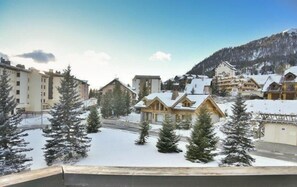 Un village enneigé, avec ses maisons traditionnelles en bois et une chaîne de montagnes en toile de fond.