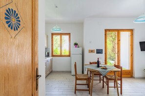 A dining area with a table, chairs, and a view of greenery outside.