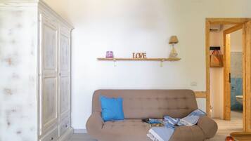 Un saló amb un sofà, un armari, una estanteria amb el lema 'LOVE' i una làmpada.