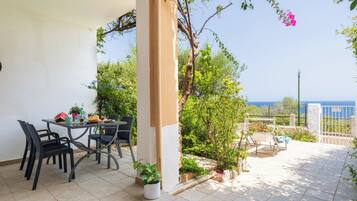 Una terrazza con tavolo e sedie, una pianta in vaso e vista sul mare.