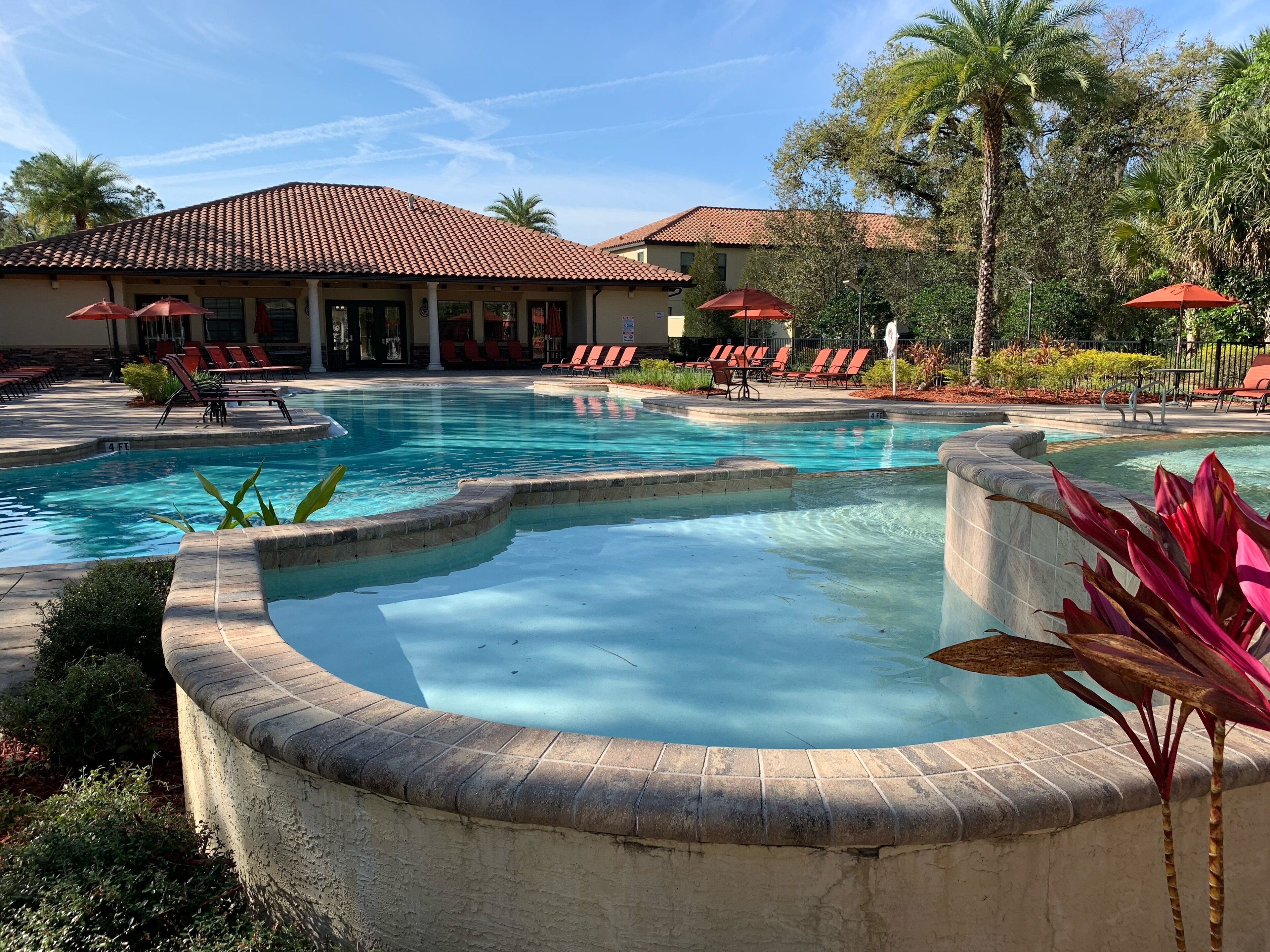 Un espace piscine doté d’un toit carrelé, de chaises longues et de palmiers.