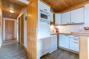 A compact kitchen with white cabinets, a built-in oven, and a dishwasher. - 130m from shops, 1st floor, view mountain, balcony, 44m², Méribel-Mottaret (Méribel - Les Allues)