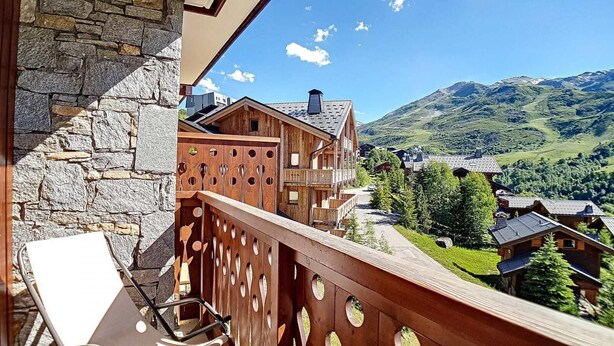 Una cabaña de madera con balcón que domina un paisaje montañoso.