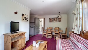 A cozy living room with a television, wooden furniture, a dining table with chairs, and a sofa. - 200m from ski slopes, 1st floor, balcony, tv, 50m², Les Menuires (Les Menuires)