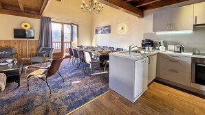 A modern kitchen with a built-in dishwasher, a dining area with a wooden table and chairs, and a large window with curtains. - 200m from ski slopes, 2nd floor, balcony, tv, 85m², Les Menuires (Les Menuires)