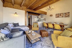 A cozy living room with a sofa, armchairs, a coffee table, and a dining area with yellow chairs and a wooden table. - 300m from shops, 2nd floor, balcony, tv, 85m², Les Menuires (Les Menuires)
