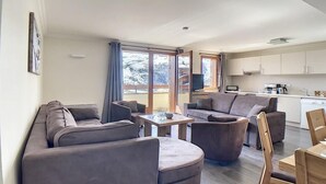 A modern living room with a sofa, armchairs, and a coffee table. There is a kitchen area with cabinets and a sink. - 200m from ski slopes, Ground floor, balcony, tv, 90m², Les Menuires (Les Menuires)