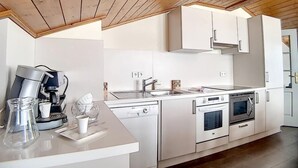 Una cocina moderna con armarios blancos, una cafetera, un fregadero y un horno.