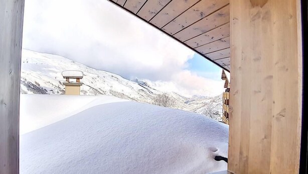 Une cabane en bois offrant une vue sur un paysage enneigé.