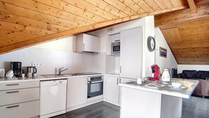 Une cuisine de taille réduite avec des meubles blancs, un lave-vaisselle, un four et un four à micro-ondes.