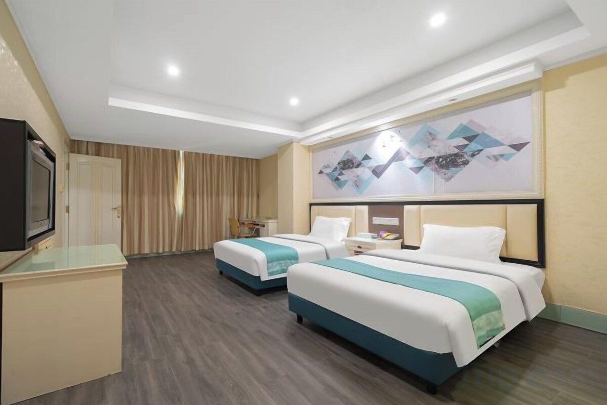 A hotel room with two beds, a TV, and a painting on the wall.