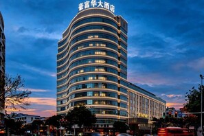 Un hotel de varios pisos con fachada curva y ventanas iluminadas.