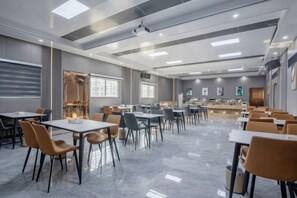 Un comedor moderno con mesas, sillas, una barra y un ventanal grande.