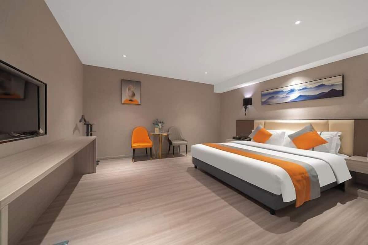 A modern hotel room with a large bed, a desk, and a chair.