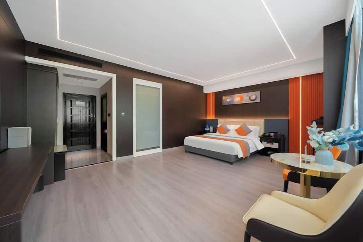 A modern hotel room with a large bed, a desk, and a seating area.
