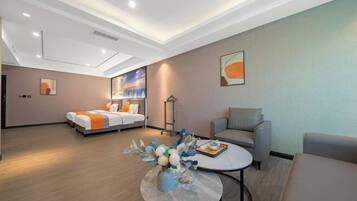Una habitación de hotel moderna con cama, sofá, mesa de centro y obras de arte en las paredes.