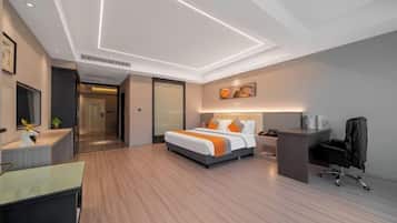 Una habitación de hotel moderna con cama, escritorio, silla y un cuadro en la pared.
