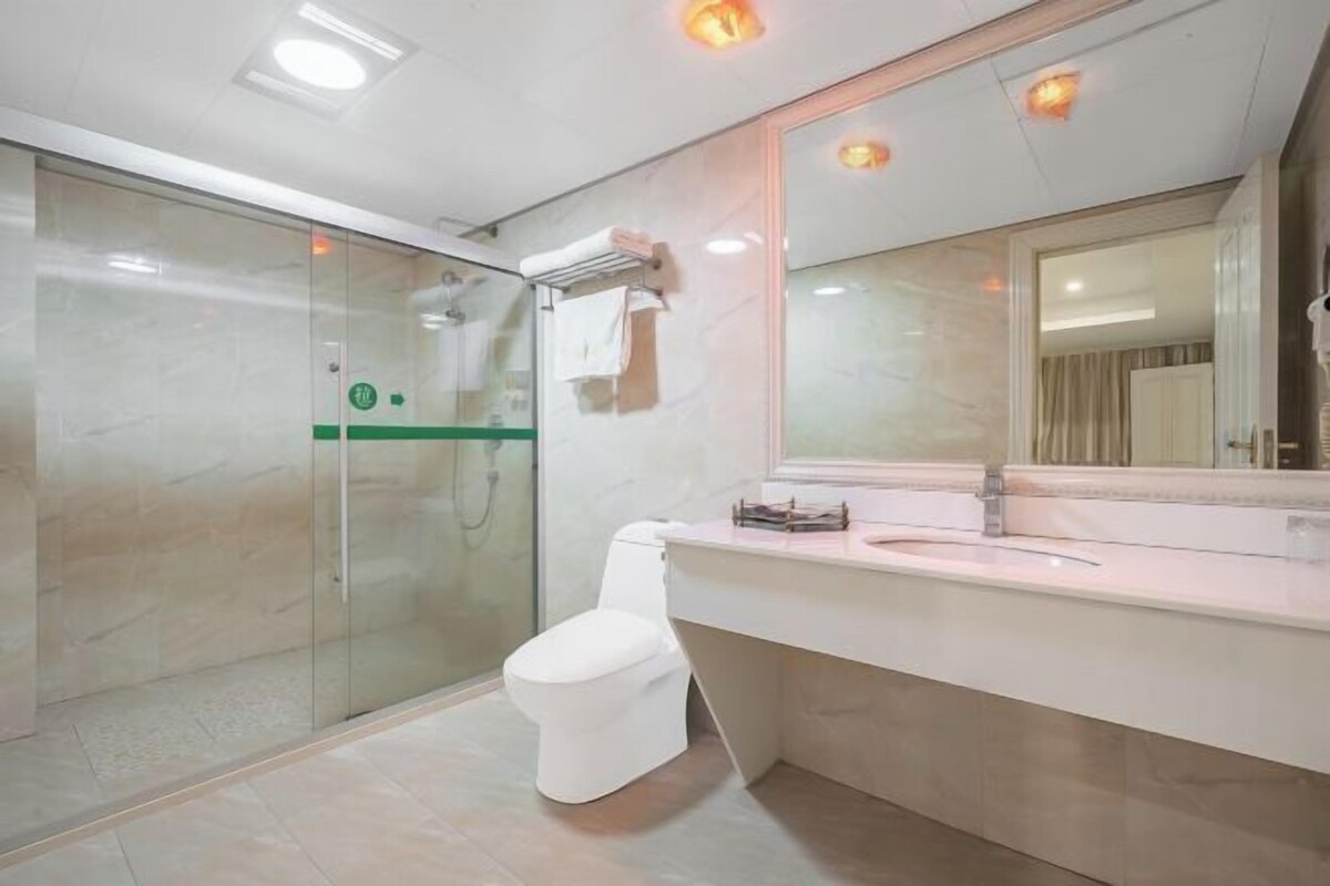 A modern bathroom with a glass shower enclosure, a white toilet, and a vanity with a mirror.