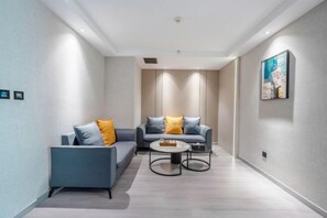 A modern living room with a sofa, armchair, and coffee table. - Hao Fu Hua Hotel (Quanzhou)