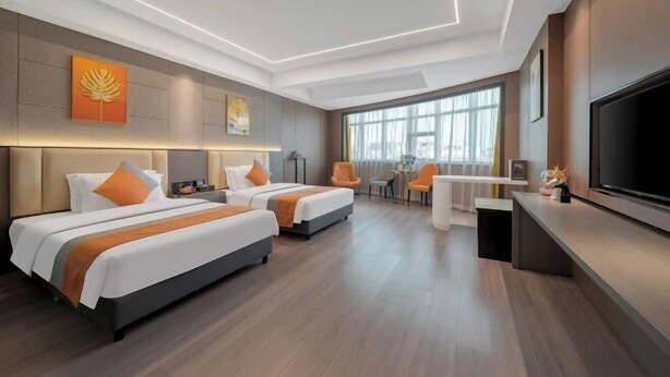 A hotel room with two beds, a TV, a desk, and a large window.
