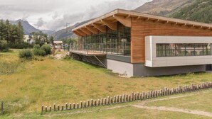 A modern building with a wooden facade and large windows, set against a mountainous backdrop. - 100m from shops, 1st floor, view street, 32m², Serre Chevalier (SERRE CHEVALIER)