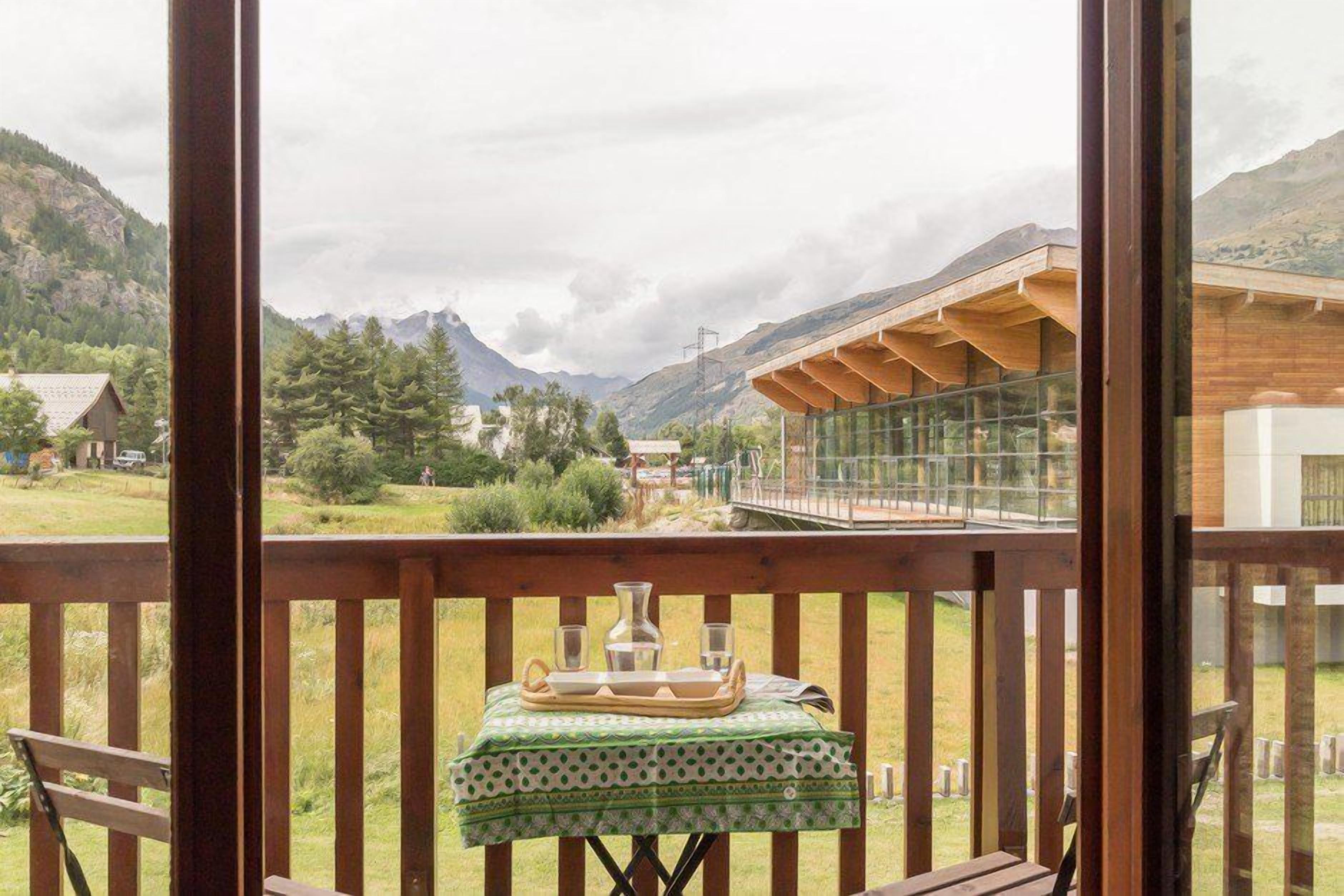 Una terraza de madera con una mesa preparada para dos, con vistas a un paisaje montañoso.