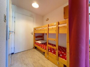 Ein Zimmer mit einem Etagenbett, einer Tür und einem kleinen Fenster.