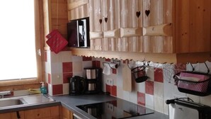 Een keuken met houten kastjes, een magnetron, een koffiezetapparaat en een broodrooster.
