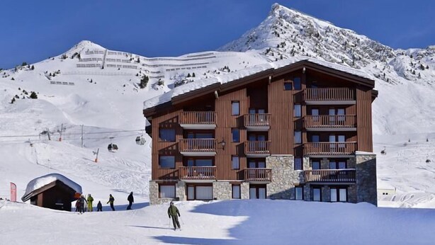 Een hotel met meerdere verdiepingen en balkons, gelegen op een besneeuwde berghelling.