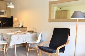Zona pranzo con tavolo apparecchiato per due, una sedia, una lampada e uno specchio a parete.