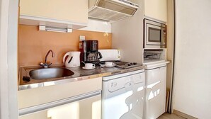 Eine kompakte Küchenzeile mit Spüle, Kaffeemaschine, Mikrowelle und Backofen.